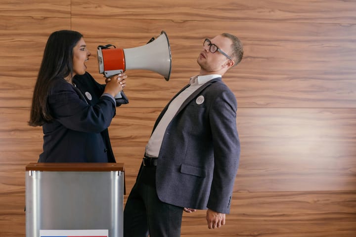 A woman shouts at a man with a megaphone